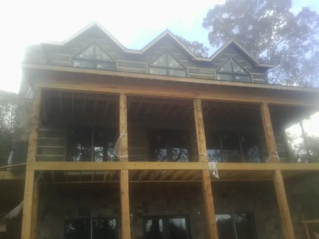 Dormers and porch framing on a large log home under construction — Roof Coating work by our crew in Moorhead
