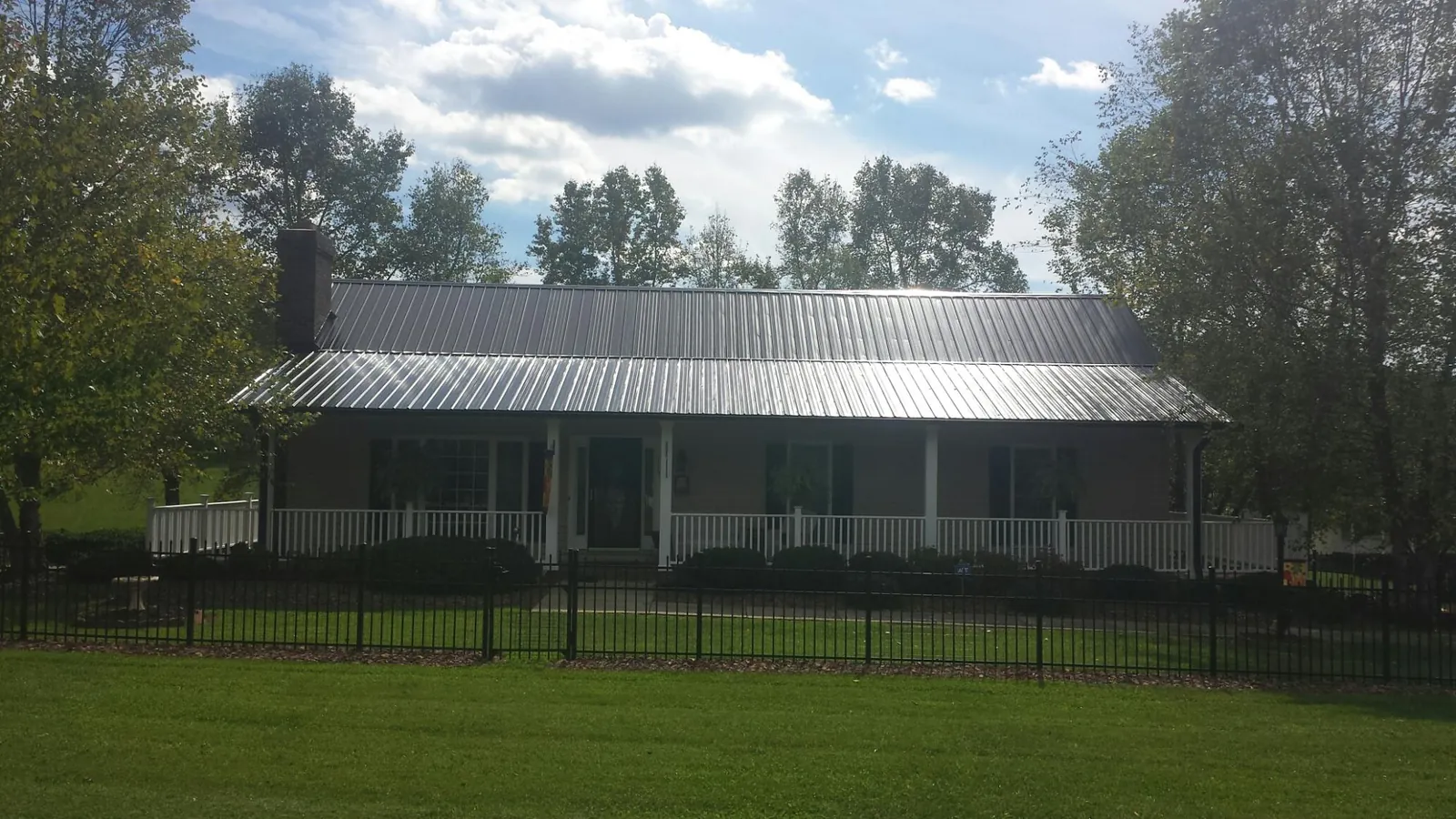 Gray metal roof on a brick ranch with a full width front porch — Gutter Guard Installation work by our crew in Moorhead