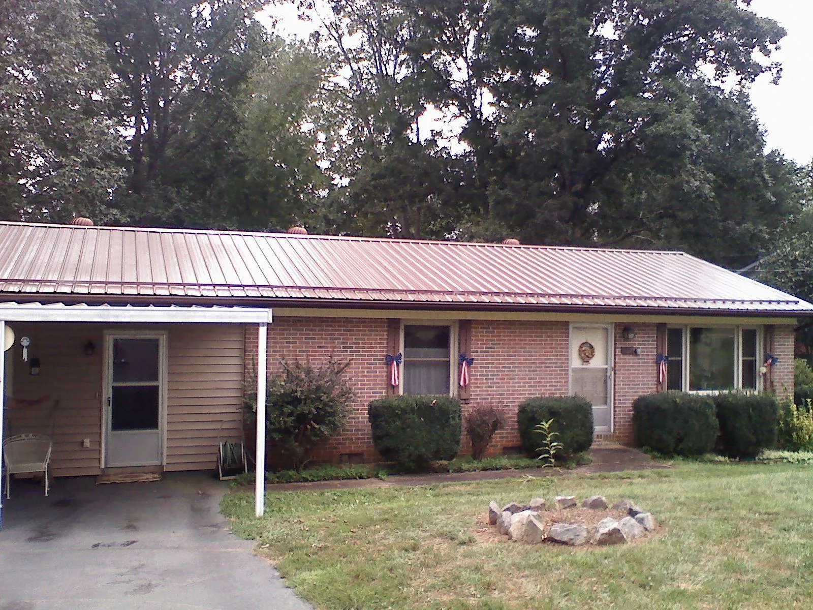 Bronze metal roof and carport on a brick ranch home — Roof Repair work by our crew in Moorhead